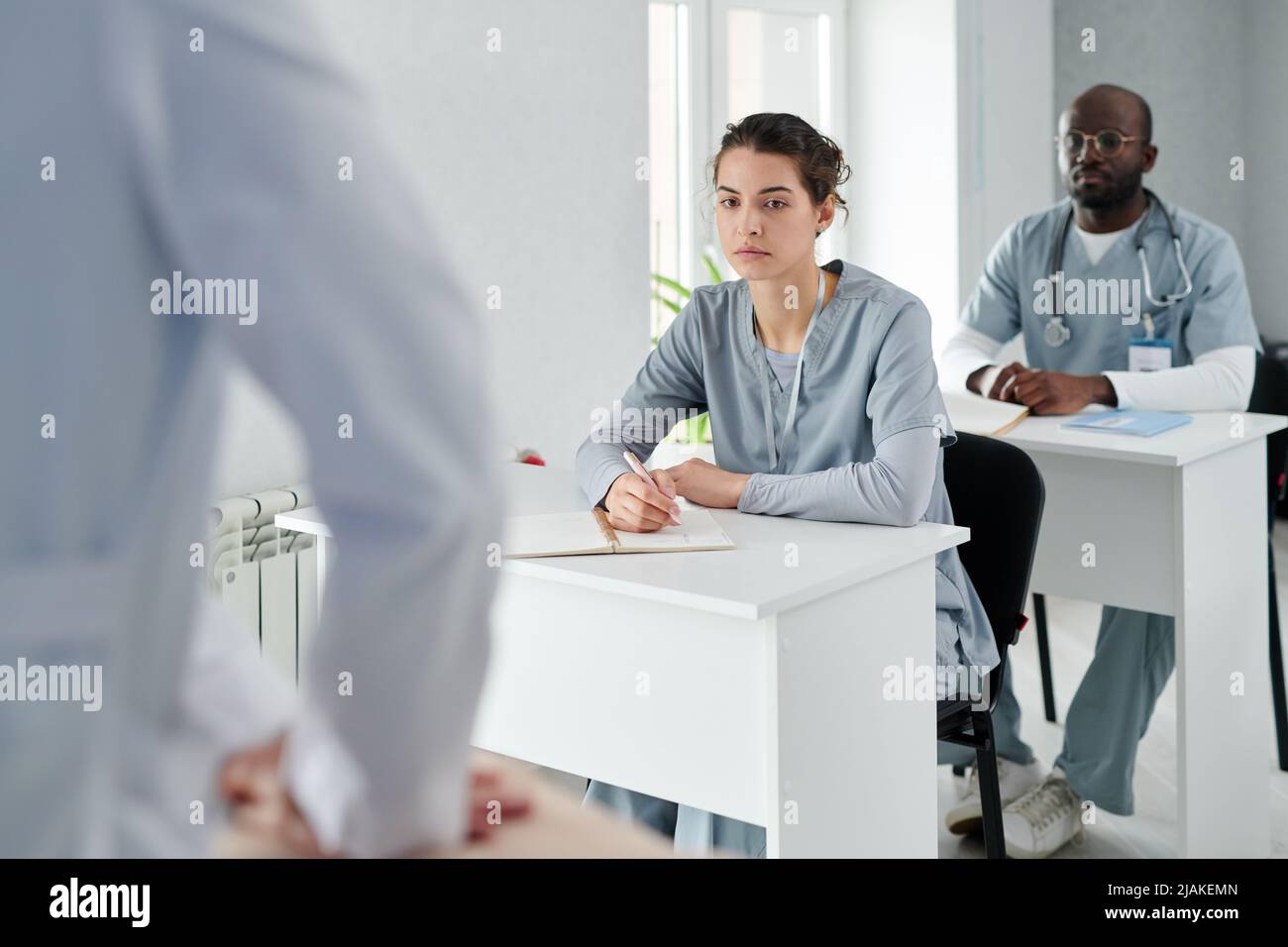 Medical students in uniform sitting at desks learning how to provide