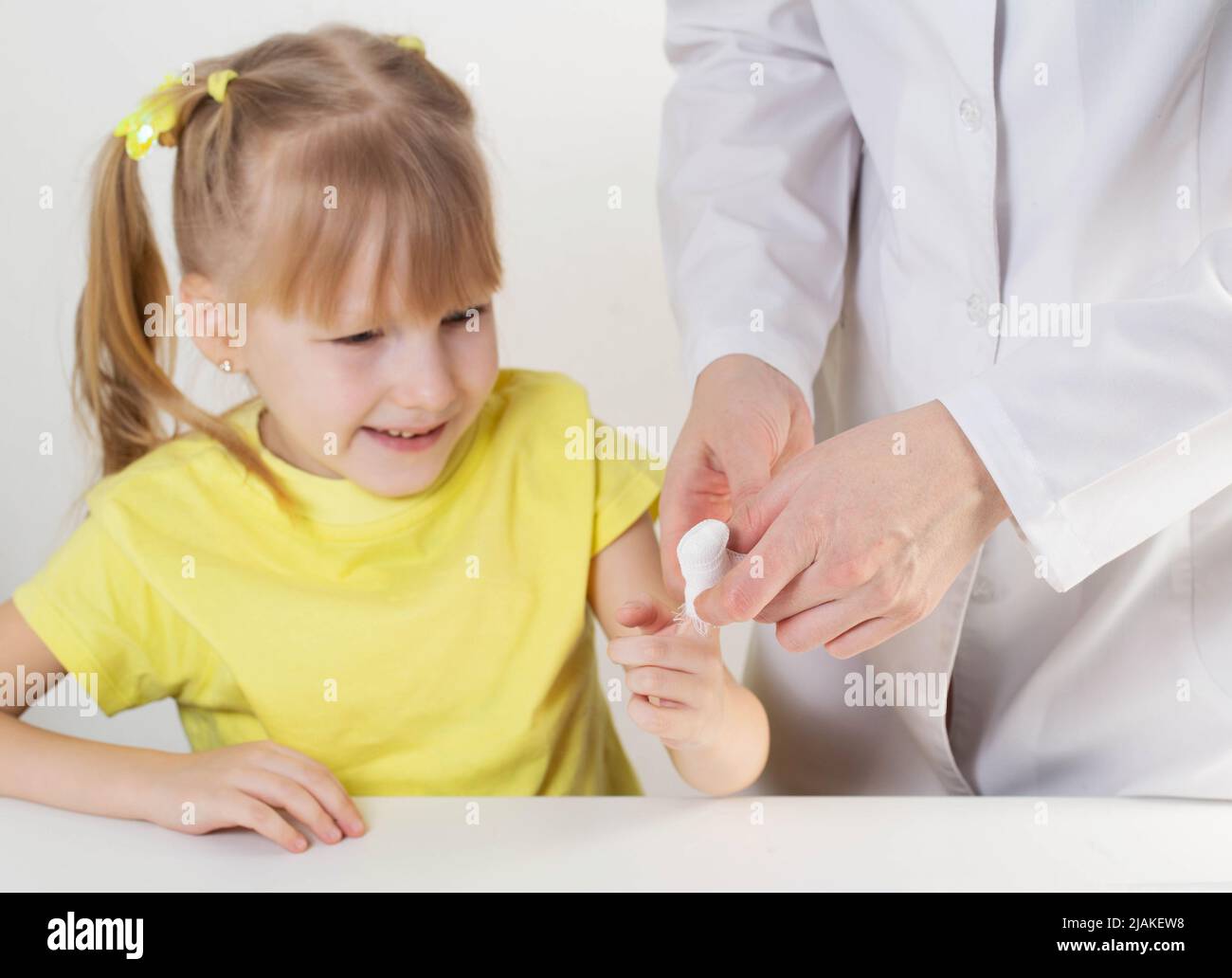 The doctor bandages the wound with a bandage, the child is a girl of 5 years Stock Photo