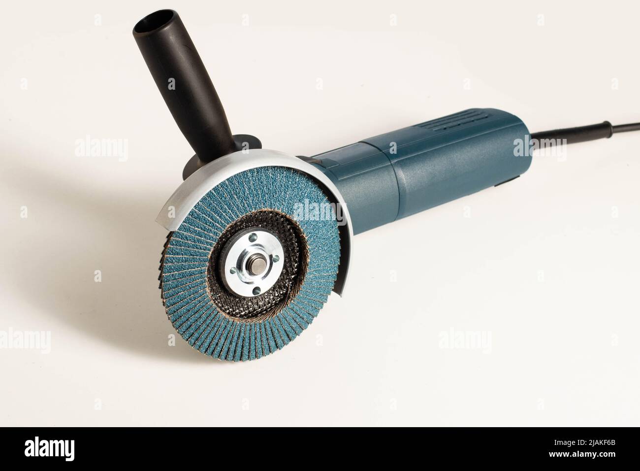 Modern professional angle grinder with a flap wheel on a white background. Power tool for work. Sanding wood and metal. Close-up. Vibration damping fu Stock Photo