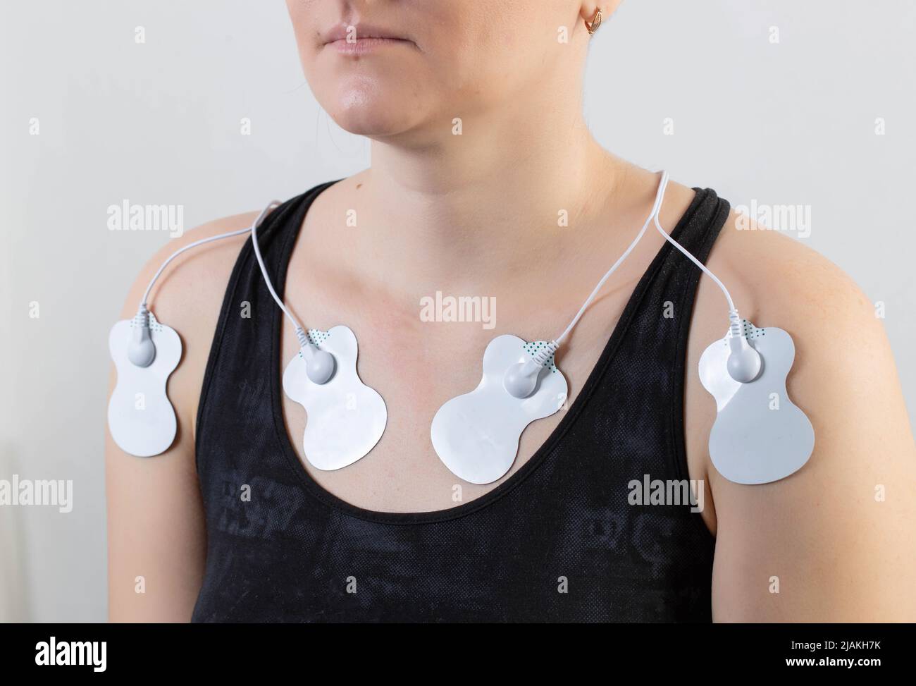 Treatment and relaxation of muscles on the human body with the help of an electronic apunctuator medical device. Skin massage, home physiotherapy. Stock Photo