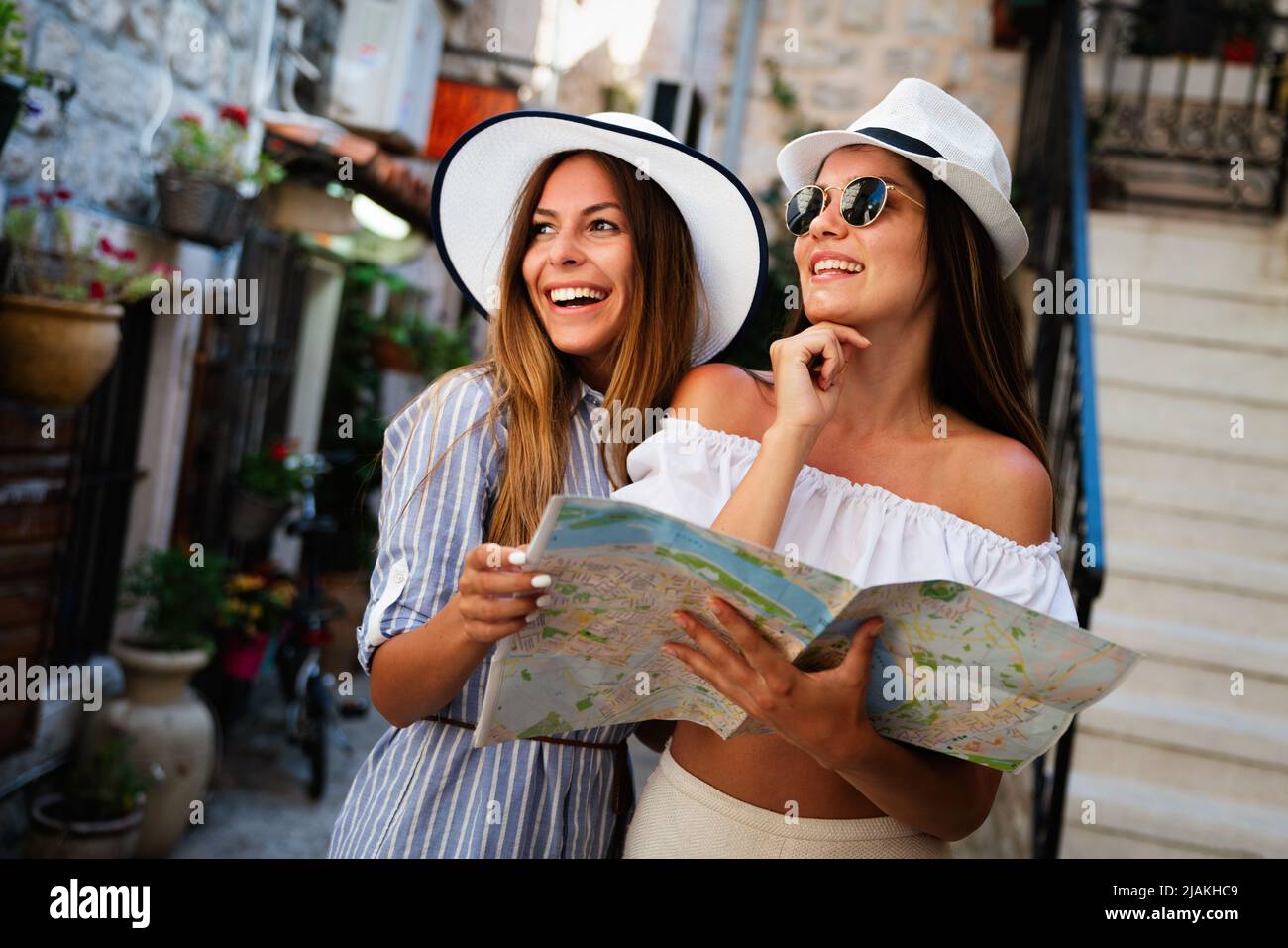 Happy young women with map in city. Travel tourist people fun concept. Stock Photo