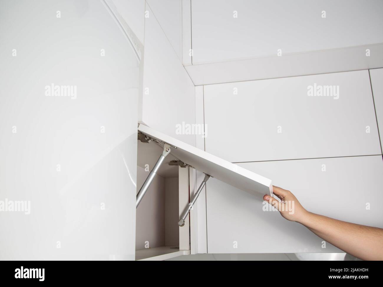 A furniture assembly worker holds a retractable gas spring to open and support a cabinet door. Modern furniture fittings Stock Photo