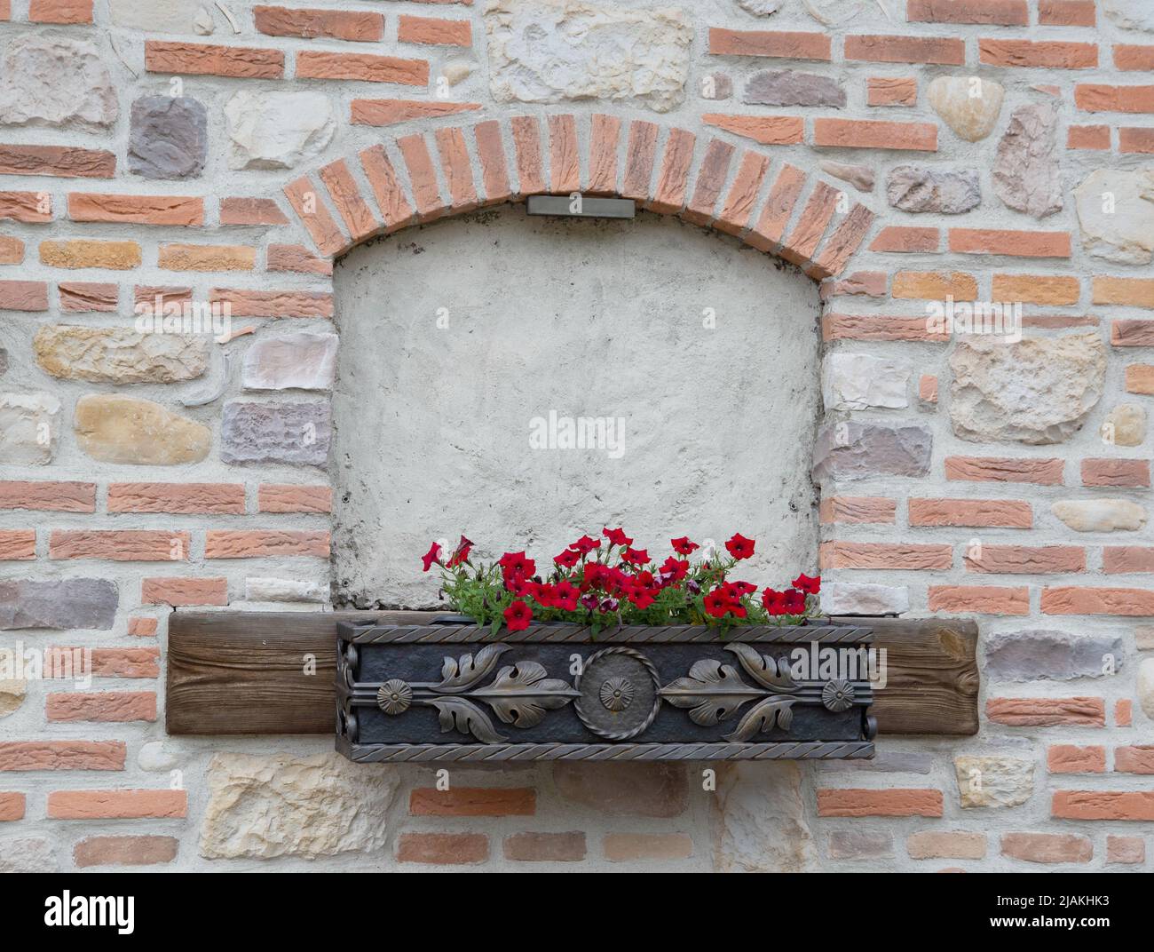 Laid down antique semicircular window in a brick wall with a flowerpot Stock Photo