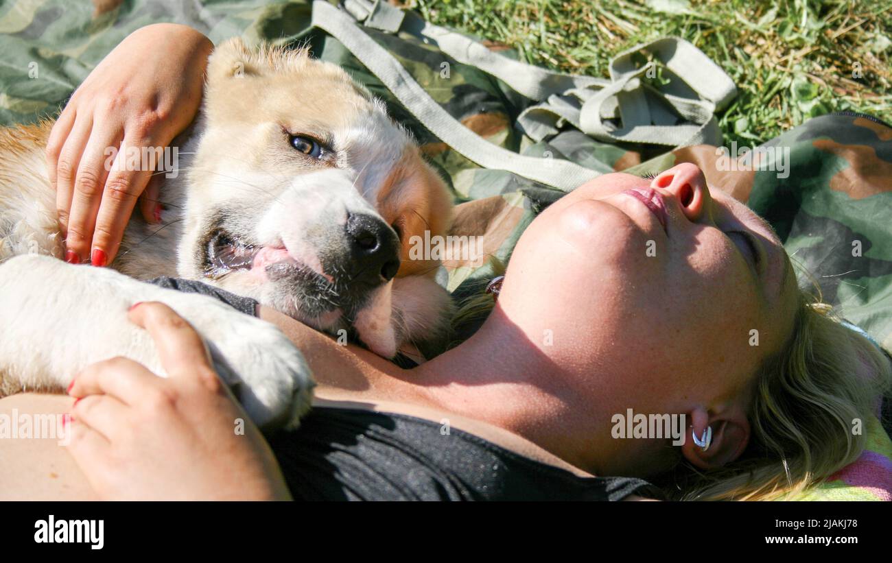 The girl is lying with the dog. Central Asian Shepherd Dog, Alabay or Alabai Stock Photo