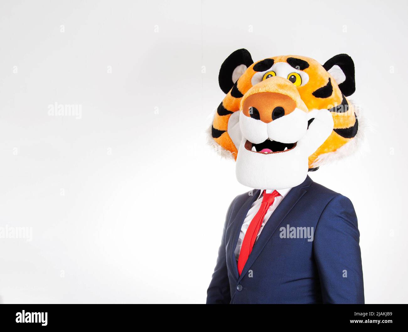 A man in a business suit and a funny tiger mask on his head on a white background. Copy space for text Stock Photo