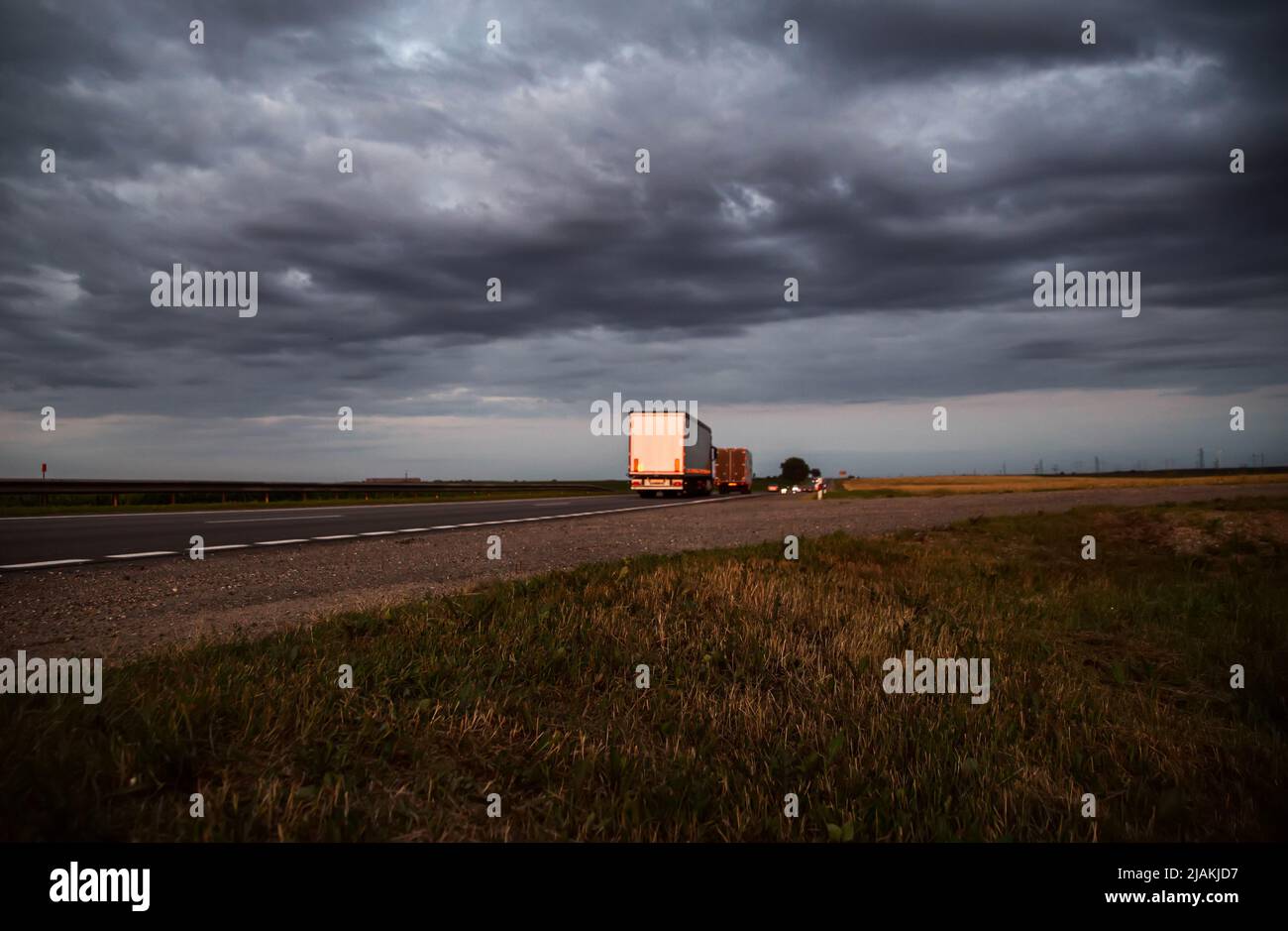 A column of trucks with trailers carry cargo in the evening against a cloudy sky with clouds. Direct FTL transportation model. Copy space for text Stock Photo
