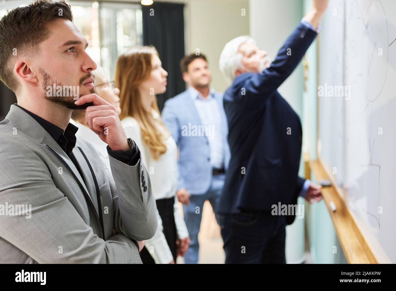 Thoughtful business man at whiteboard in brainstorming workshop with ...