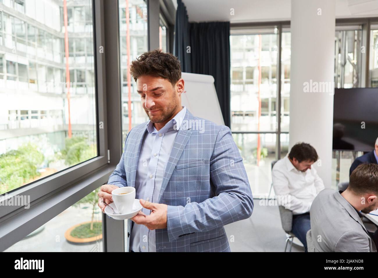 Business man relaxes drinking a cup of coffee on a break by the window in the office Stock Photo