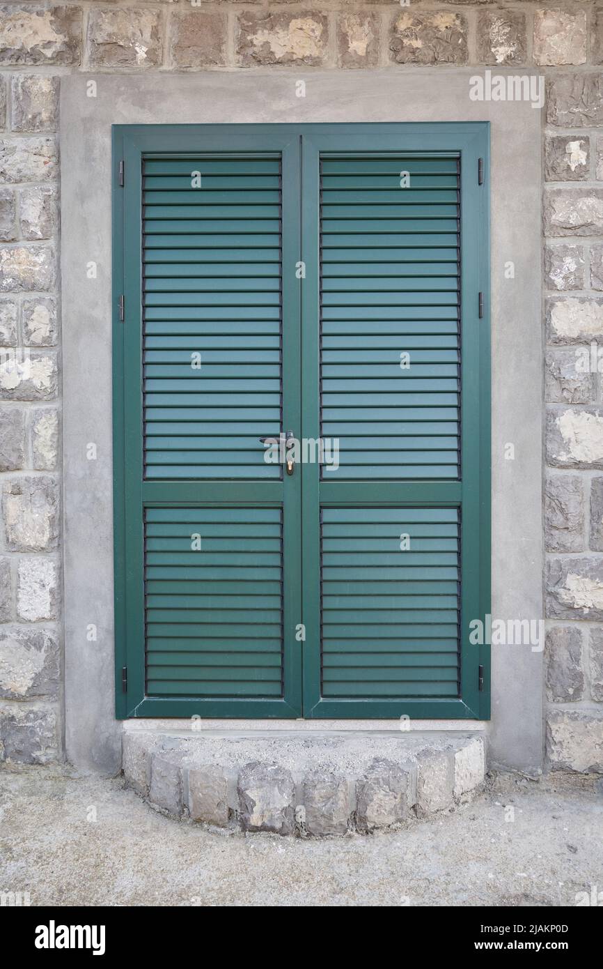 Green door with shutters at the entrance to the house Stock Photo