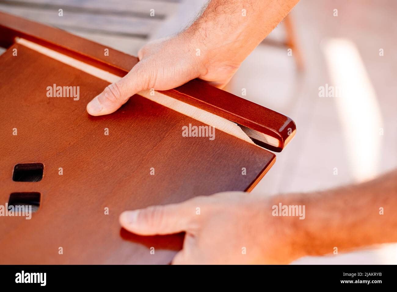 A carpenter's hands examines a chair with loose boards. Stock Photo
