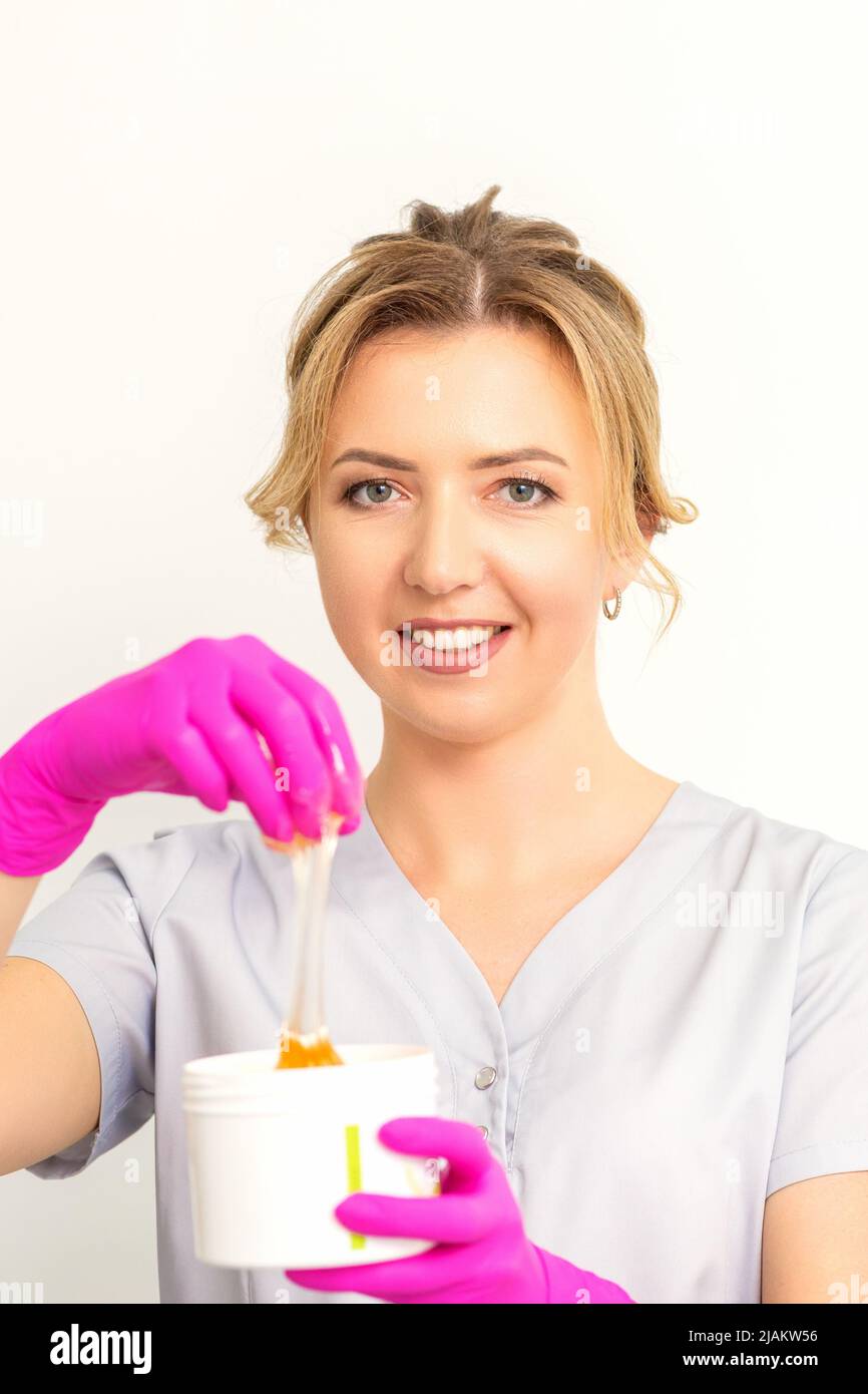 Portrait of a female caucasian beautician holding a jar of sugar paste