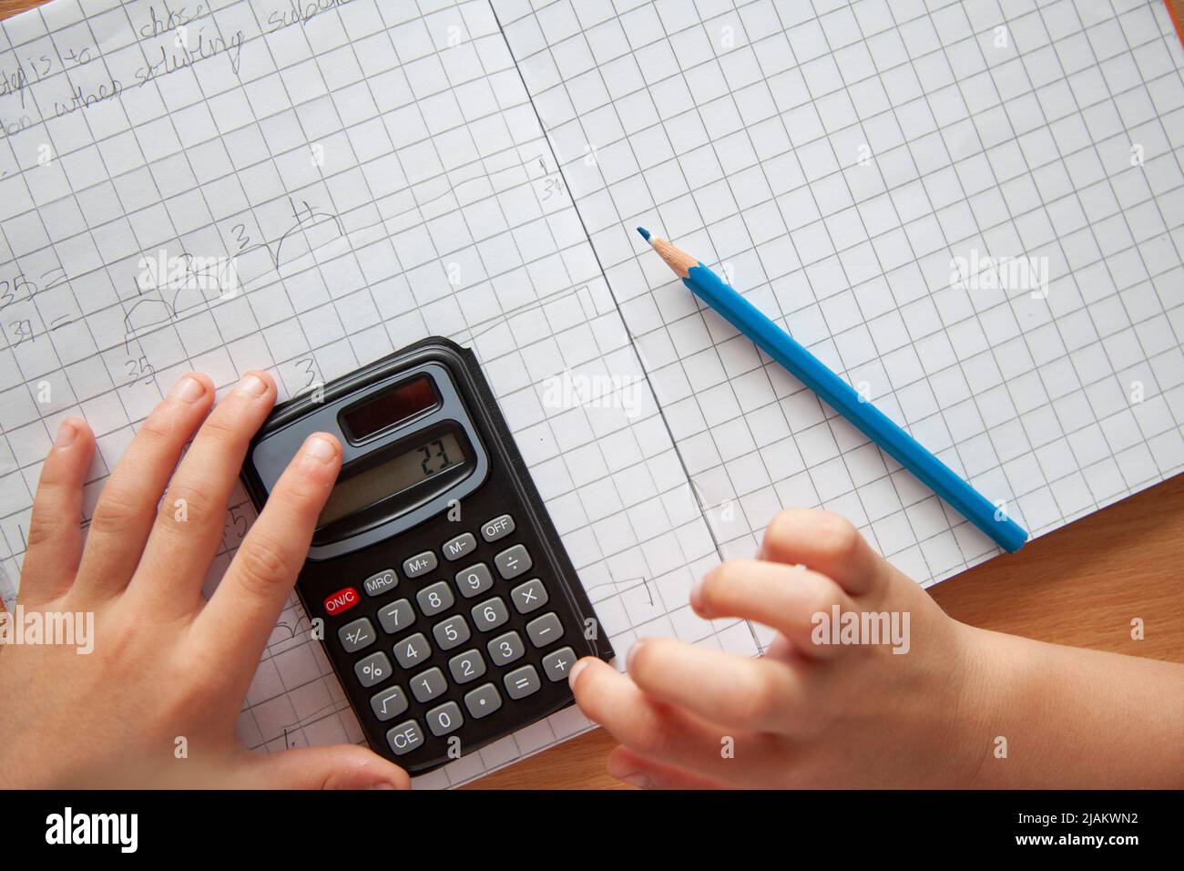 Overhead view of a child using a calculator to solve maths questions