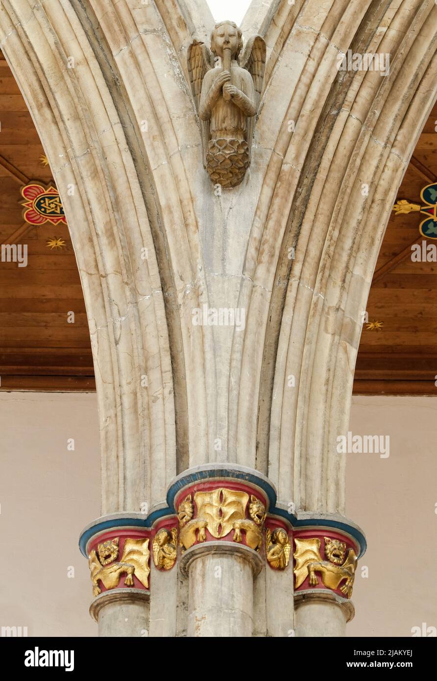 Hull, East Yorkshire, UK. May 21, 2022 An early stone carving of an angel playing music, high on arched pillars with decorative gilded emblems below Stock Photo