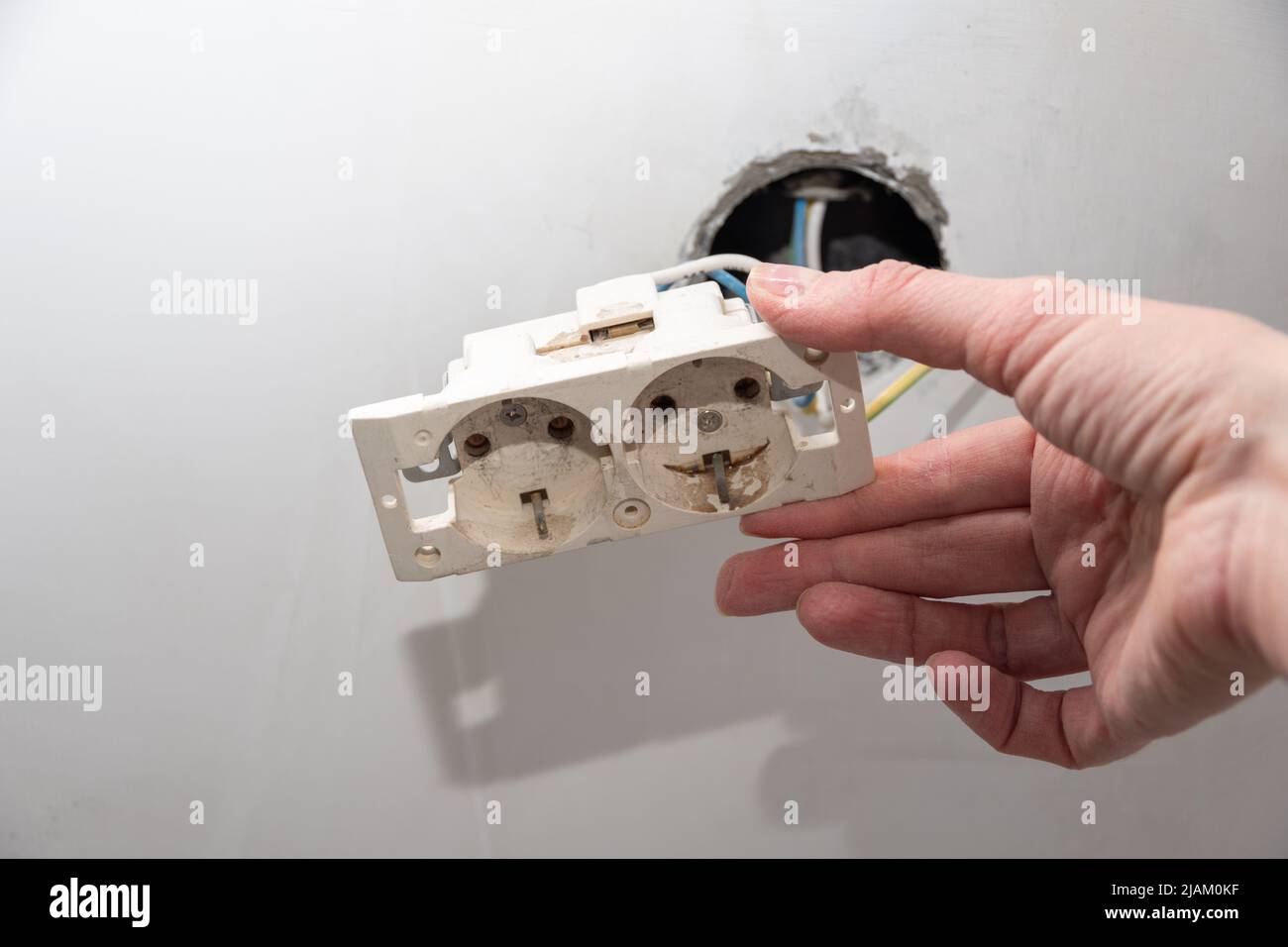 Installation of new electrical wiring, plastic socket and electric wires for future sockets on a plastered wall. Hand installing a new socket. DIY hou Stock Photo