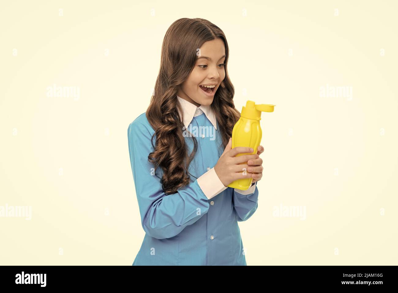 Surprised kid look at yellow plastic liquid bottle keeping mouth open