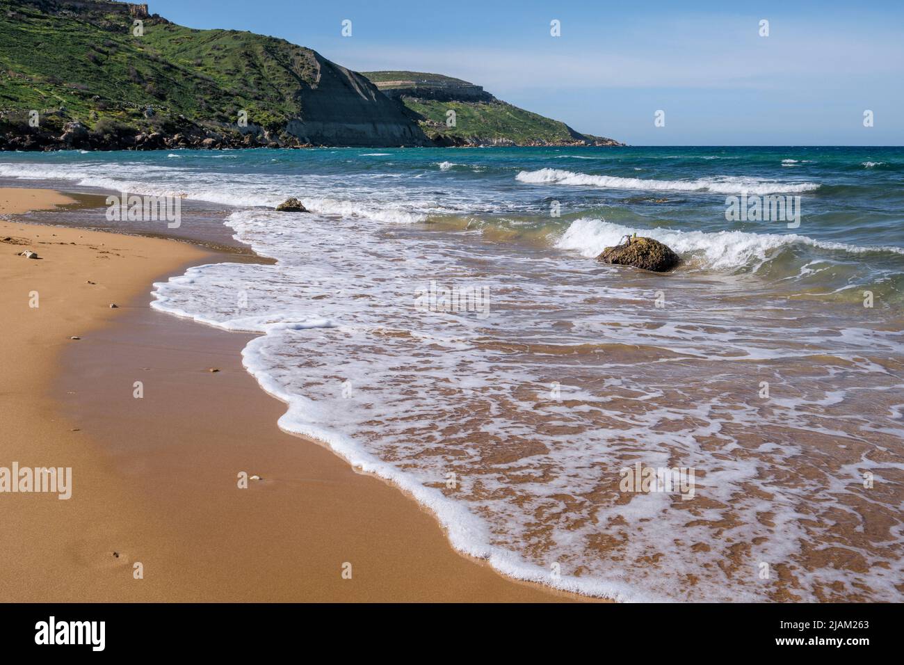 Waves breaking on the deserted sandy beach at Ramla Bay, Gozo, Malta Stock Photo