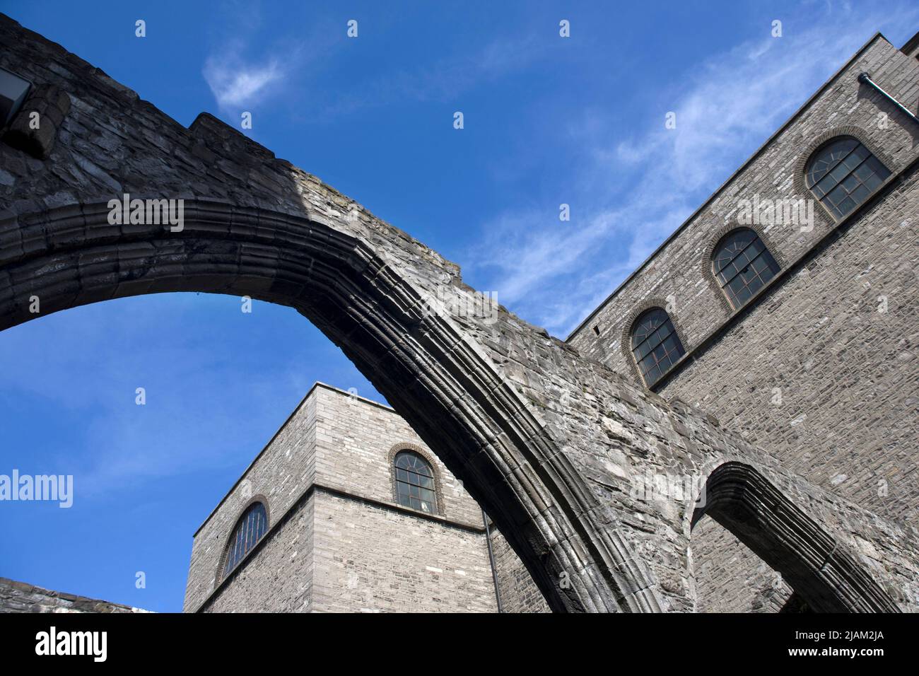 Exposed gothic arches in a disused section of St. Audeon's Church, in Dublin with the modern Catholic church behind.   One of the oldest existing chur Stock Photo