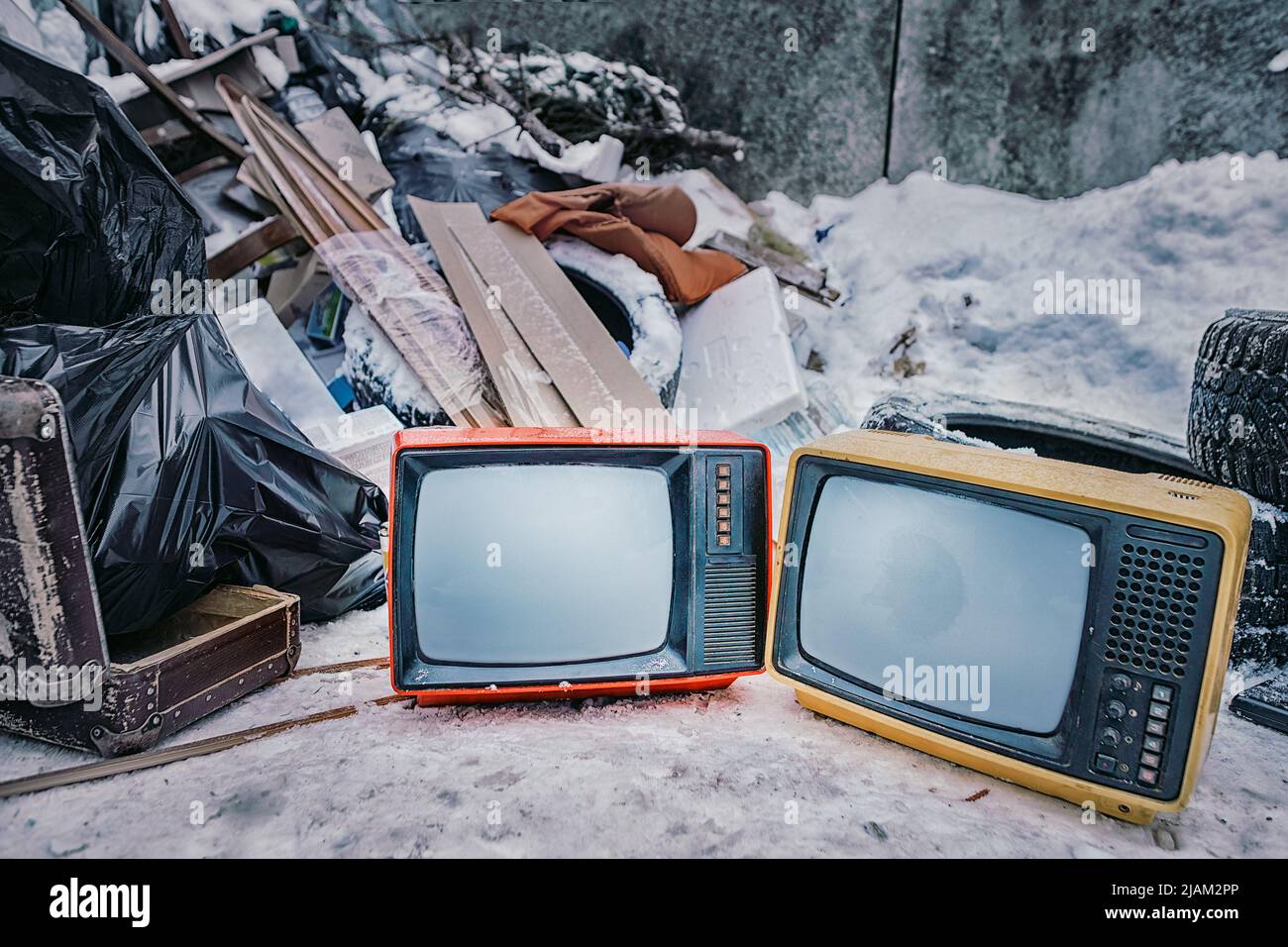 Old TVs thrown into the trash. Two bright color televisions in the middle of a pile of rubbish. Stop watching TV and obsolescence of technology theme Stock Photo