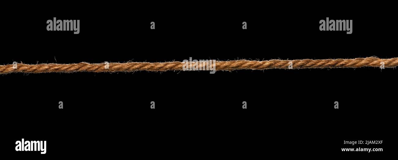 Long rough brown rope isolated on black Stock Photo