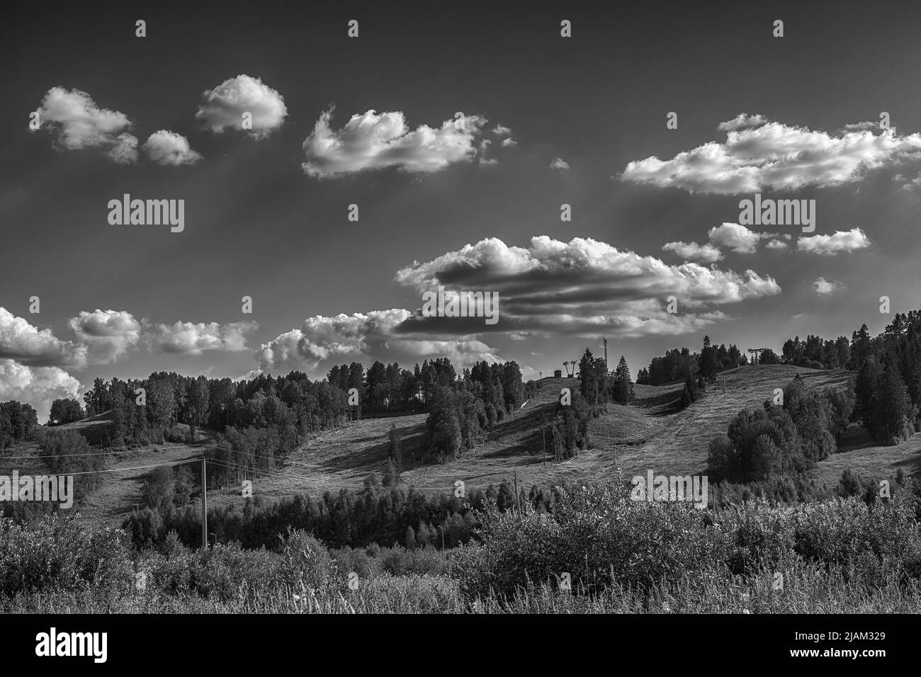 Dramatic summer scenic landscape with ski slopes in summer and dark dramatic sky. Ski resort in summer. Black and white artistic image Stock Photo