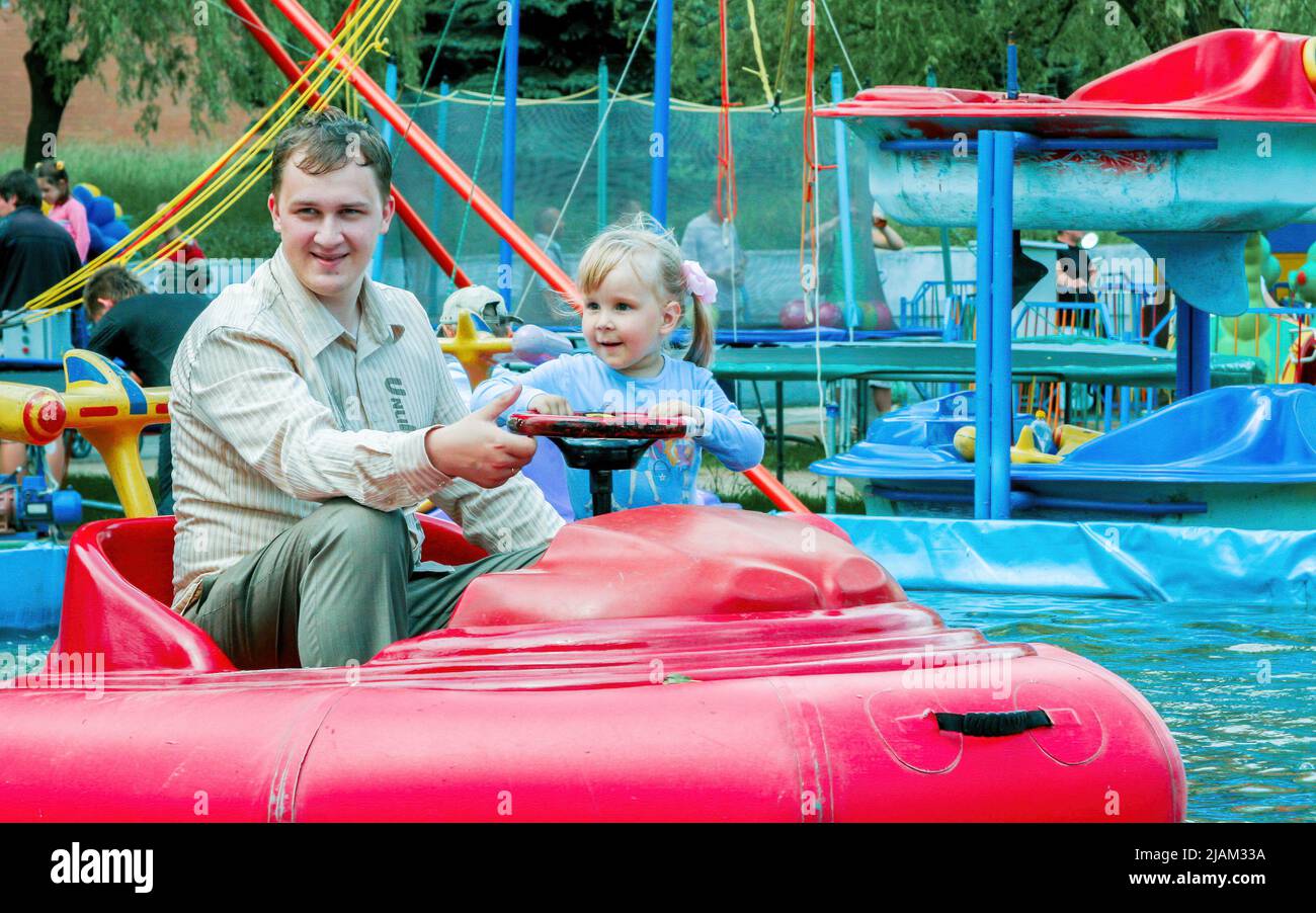 Minsk, Belarus - June 20, 2010: Father and daughter ride a boat on an attraction in the park. Stock Photo