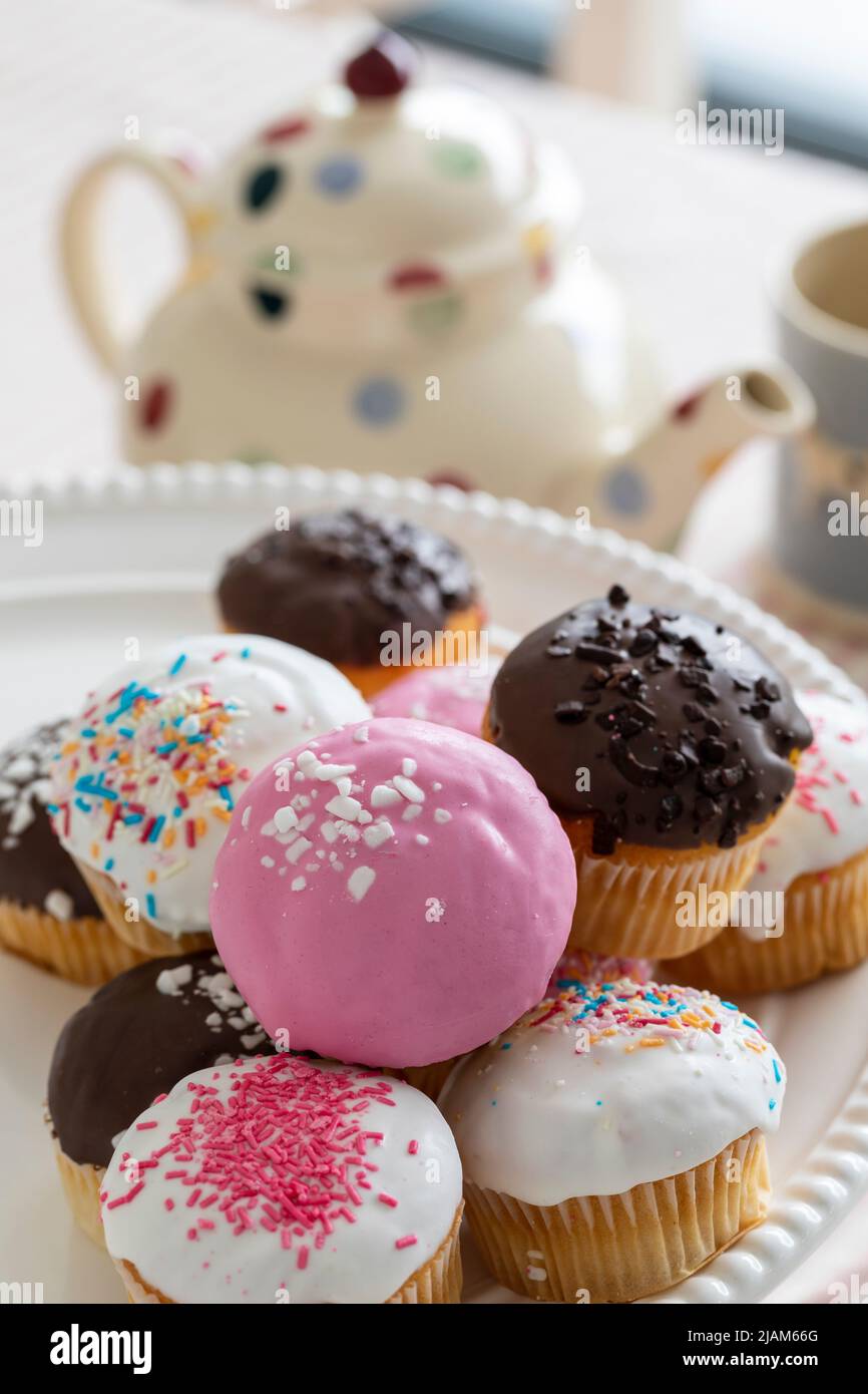 Colourful cupcakes on plate at teatime Stock Photo