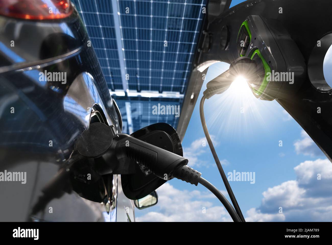 Electric car is charged from a charging station at carport that takes energy from solar panels. Close up  Stock Photo