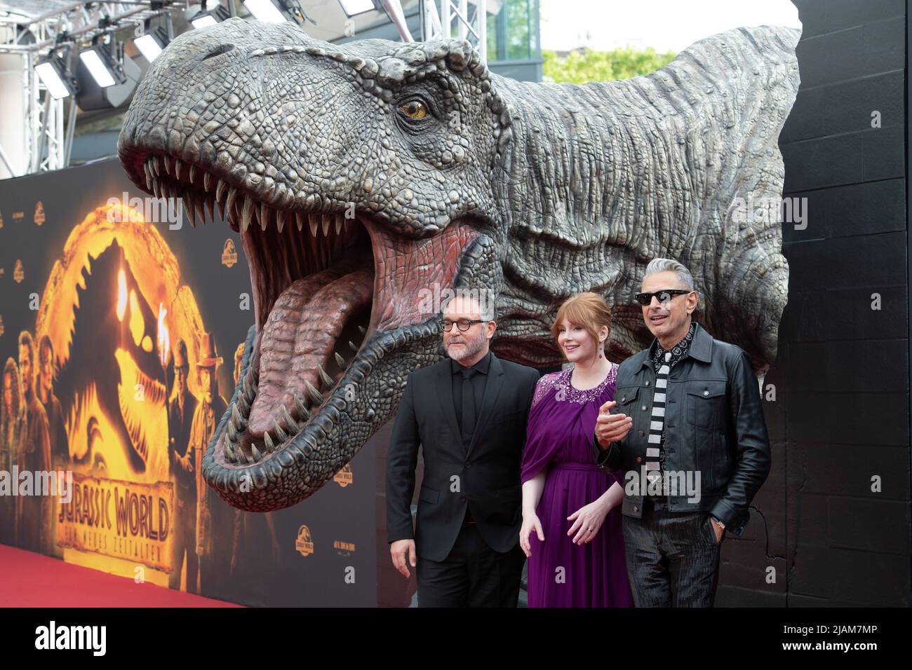 Cologne, Germany. 30th May, 2022. from left: director Colin TREVORROW, USA, actress Bryce Dallas HOWARD, USA, actor Jeff GOLDBLUM, USA, in the background a Tyrannosaurus Rex, T-Rex, character, red carpet, Red Carpet Show, arrival, arrival, film premiere JURASSIC WORLD - A NEW AGE on May 30th, 2022 in Cologne, Credit: dpa/Alamy Live News Stock Photo