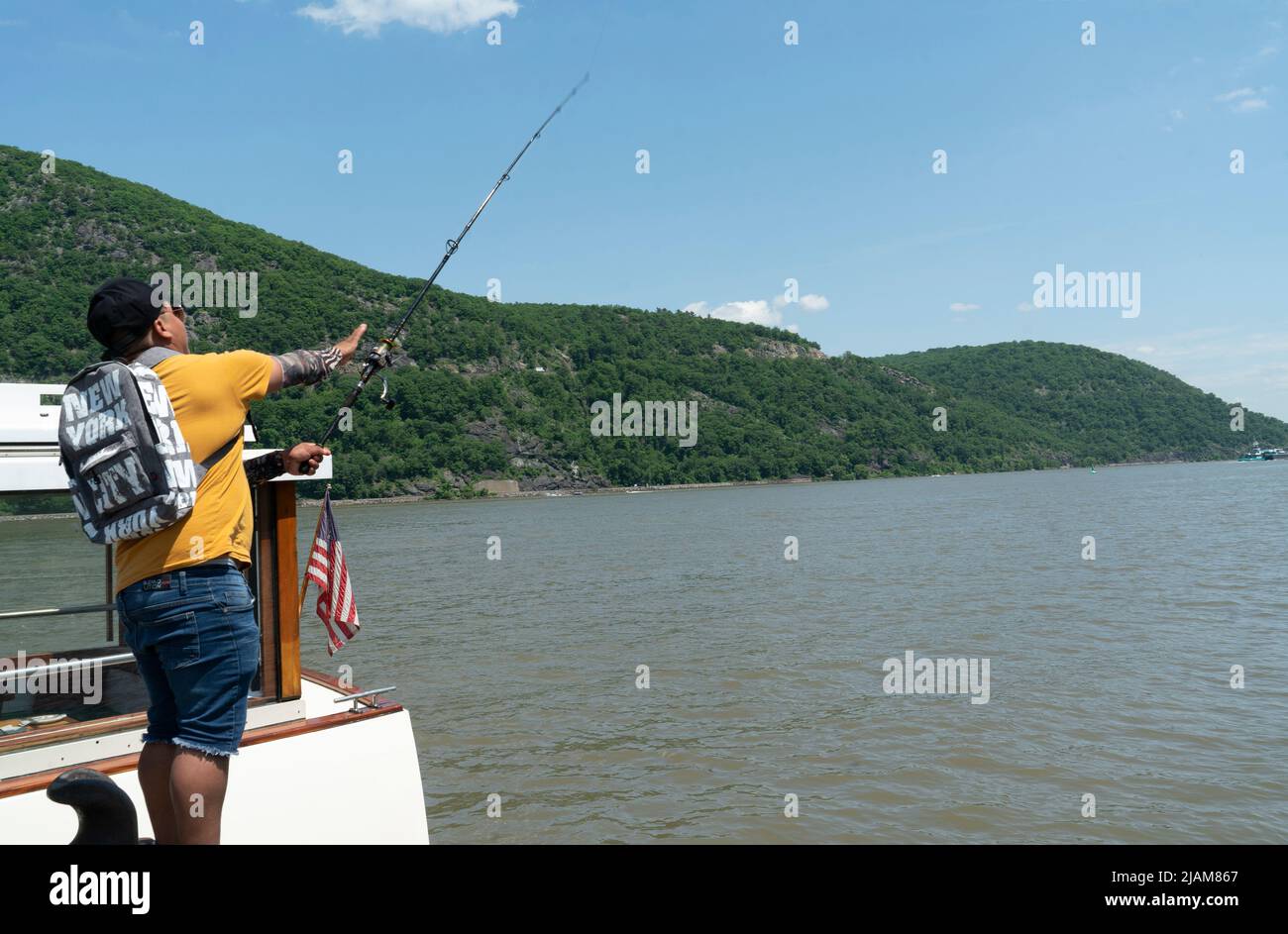 A man fishing in the Hudson River from the dock at Bear Mountain State