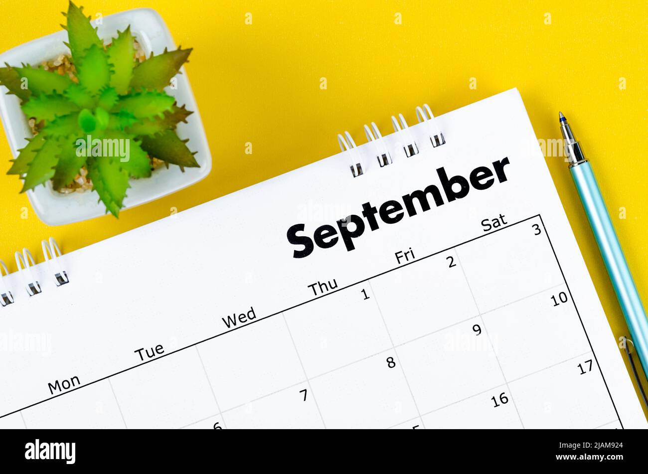 The September 2022 desk calendar and pen with plant pot on yellow ...