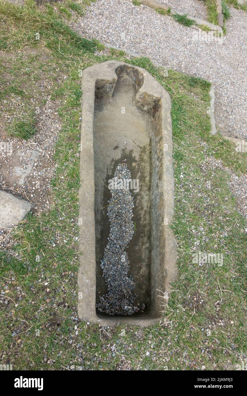 Looking down on a stone coffin in the ground outside the ruins of Whitby Abbey, Whitby, North Yorkshire, UK. Stock Photo