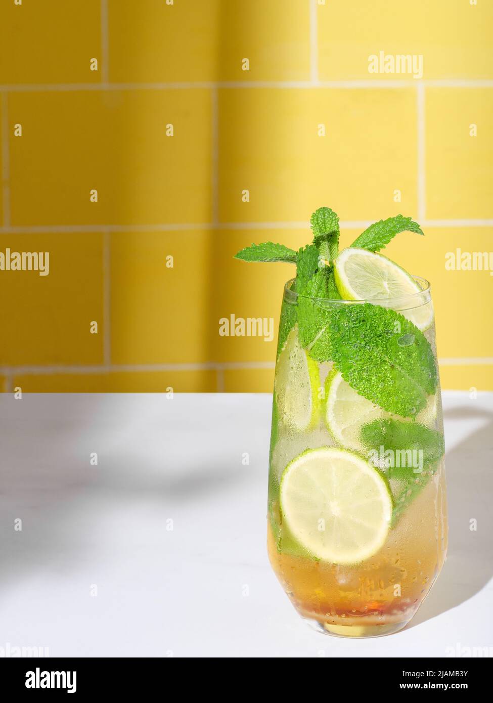 Mojito or virgin mojito long rum drink with fresh mint, lime juice, cane sugar and soda. On yellow background. Stock Photo