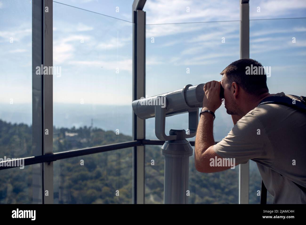 Young man watching mountain landscape through binoculars Stock Photo