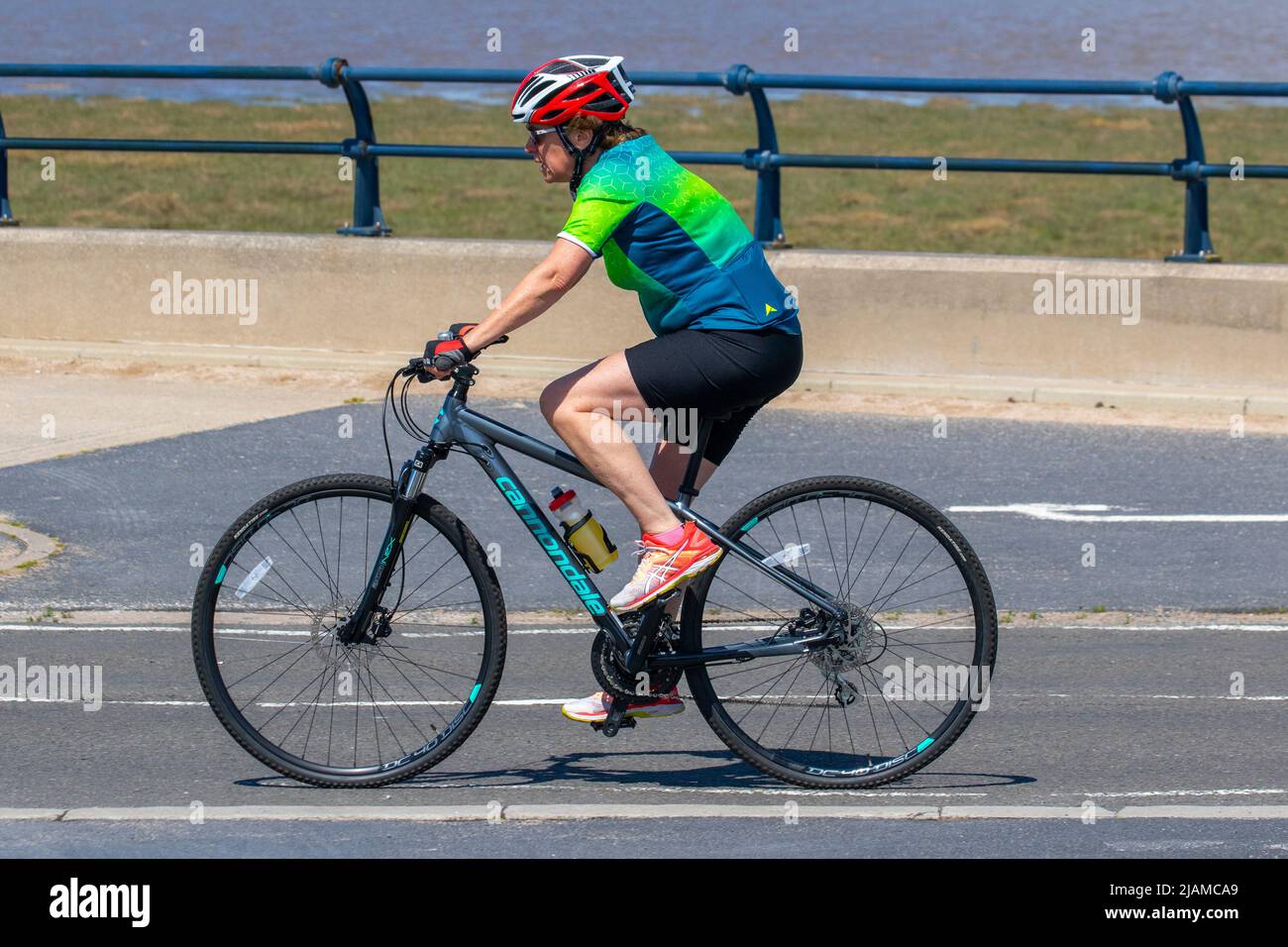 Female cyclist riding Cannondale womens sports biicycle in Southport, Merseyside.  Uk Weather.  31 May 2022. A fine bright sunny start to the day in the north-west coastal resort. Temperatures are expected to rise with the prospect of a warm June holiday Jubilee celebration weekend.  Credit; MediaWorldImages/AlamyLiveNews Stock Photo