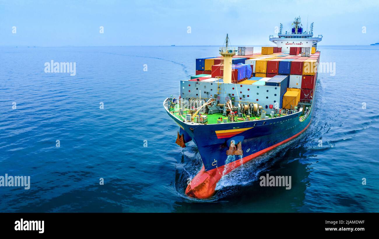 Aerial in front view of cargo ship carrying container and running for