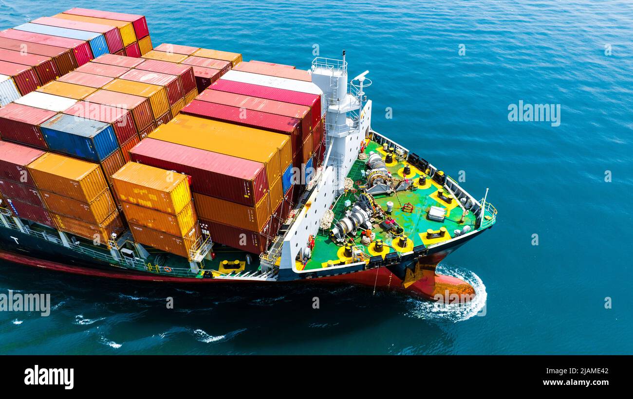 Aerial side view of cargo ship carrying container and running for