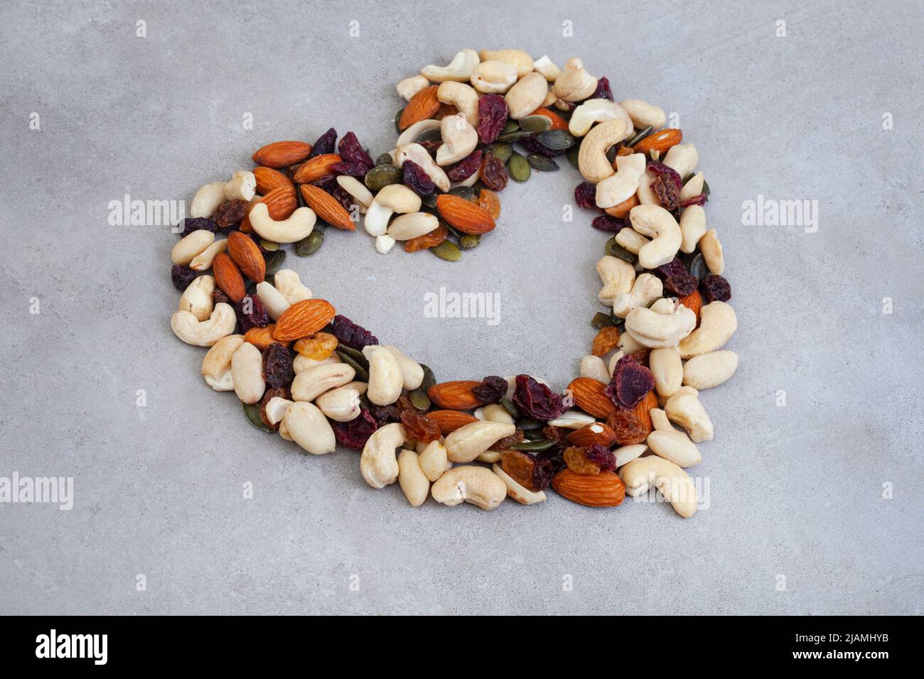 heart shape made of nut and fruit mix on mottled grey with copy space Stock Photo