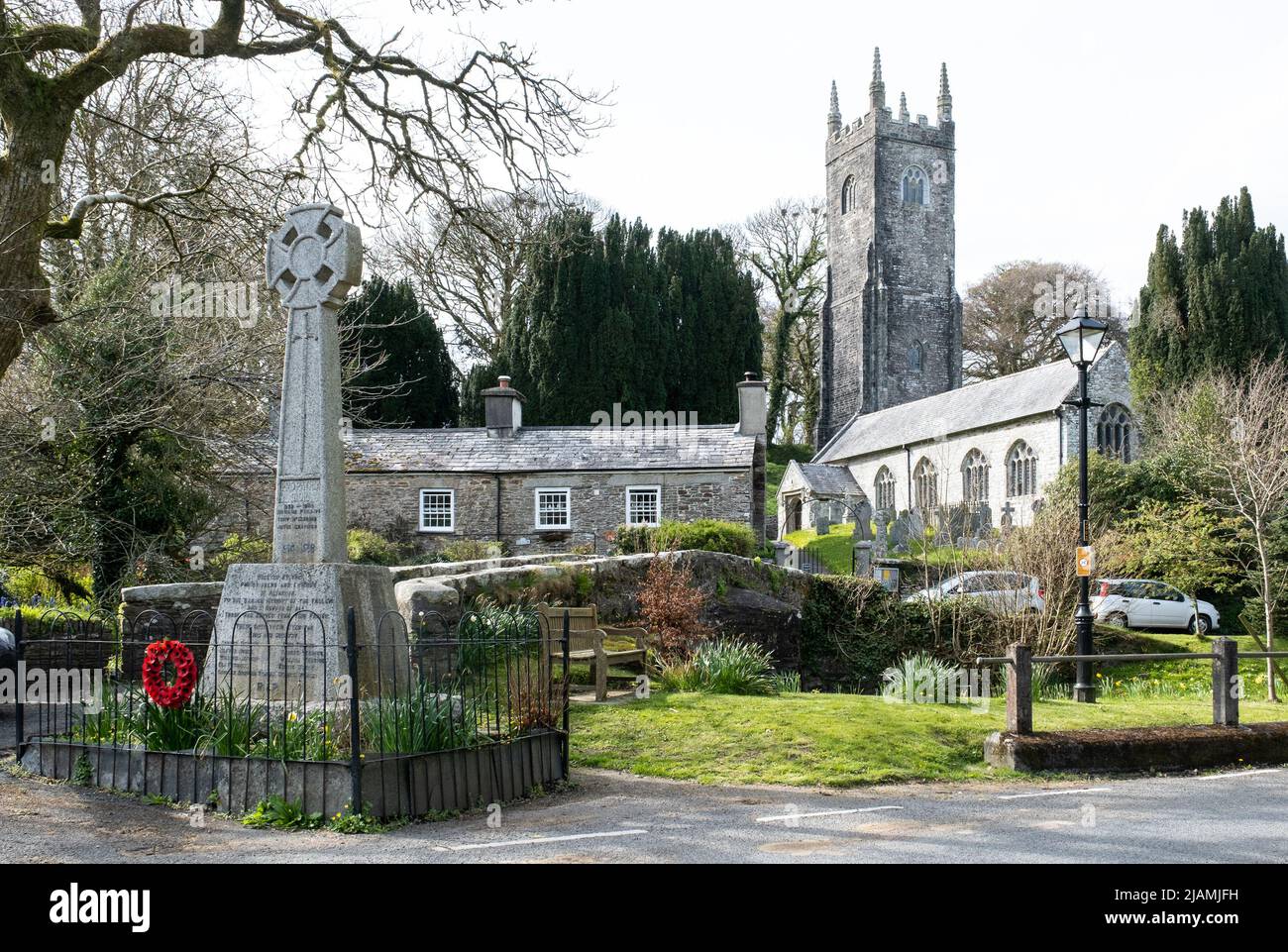 Church, houses, stone bridge and traditional Cornish stone cross with poppy wreath memorial at the centre of the hamlet of Altarnun, Cornwall. Stock Photo