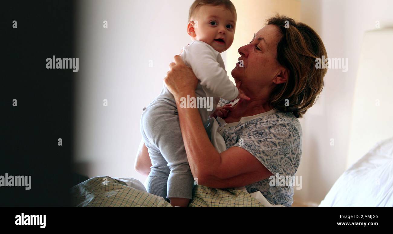 Candid family moment, grand-mother with baby grandson in bed morning