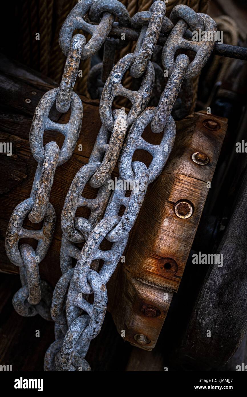 Heavy iron anchor chains wound around a wooden coil. Strong, reliable