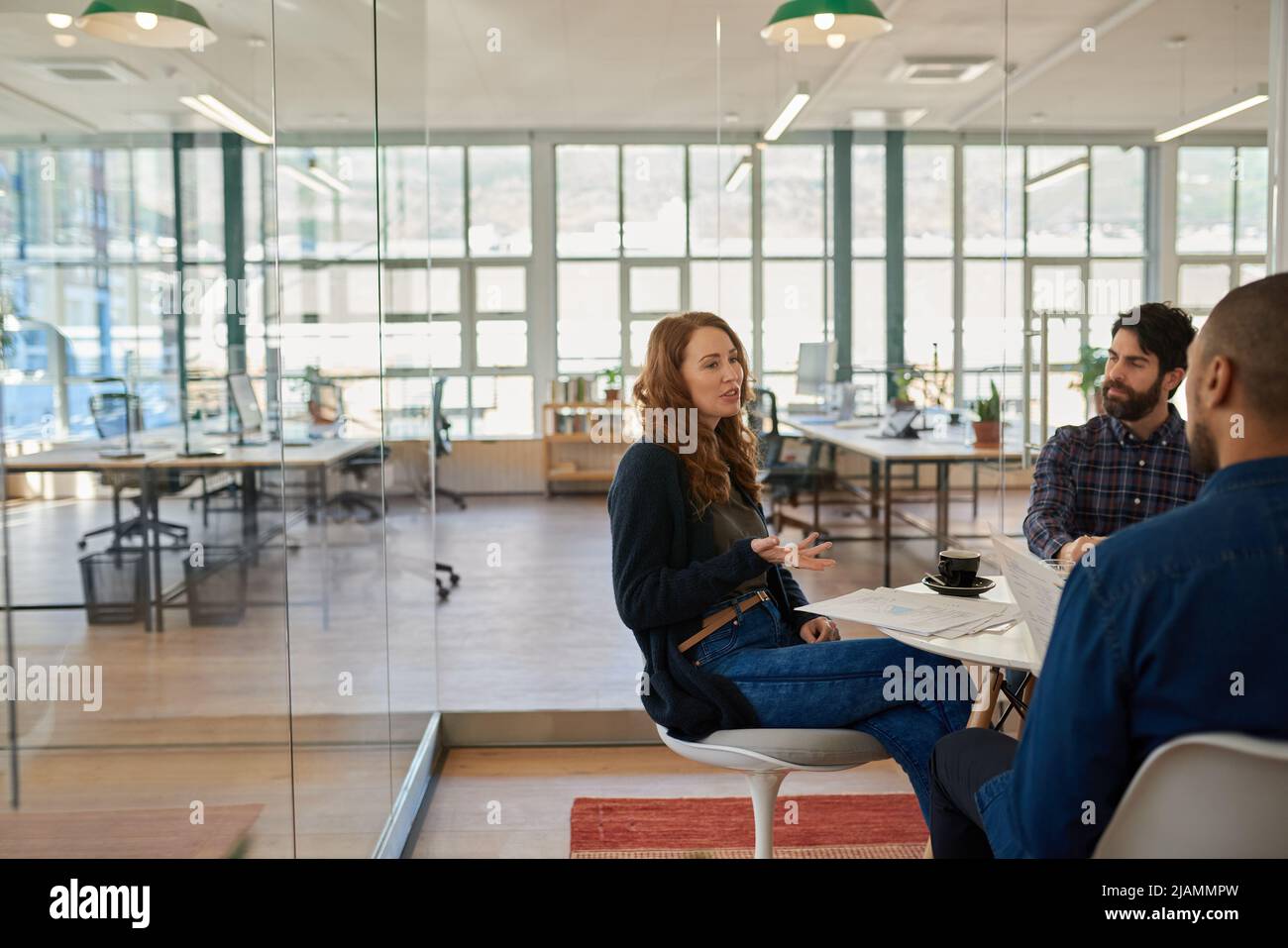 Young businesswoman speaking with two male coworkers during a casual meeting Stock Photo