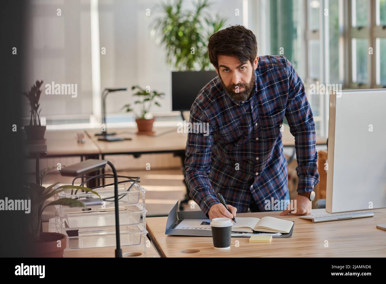 Focused businessman leaning over his desk and writing in a notebook Stock Photo