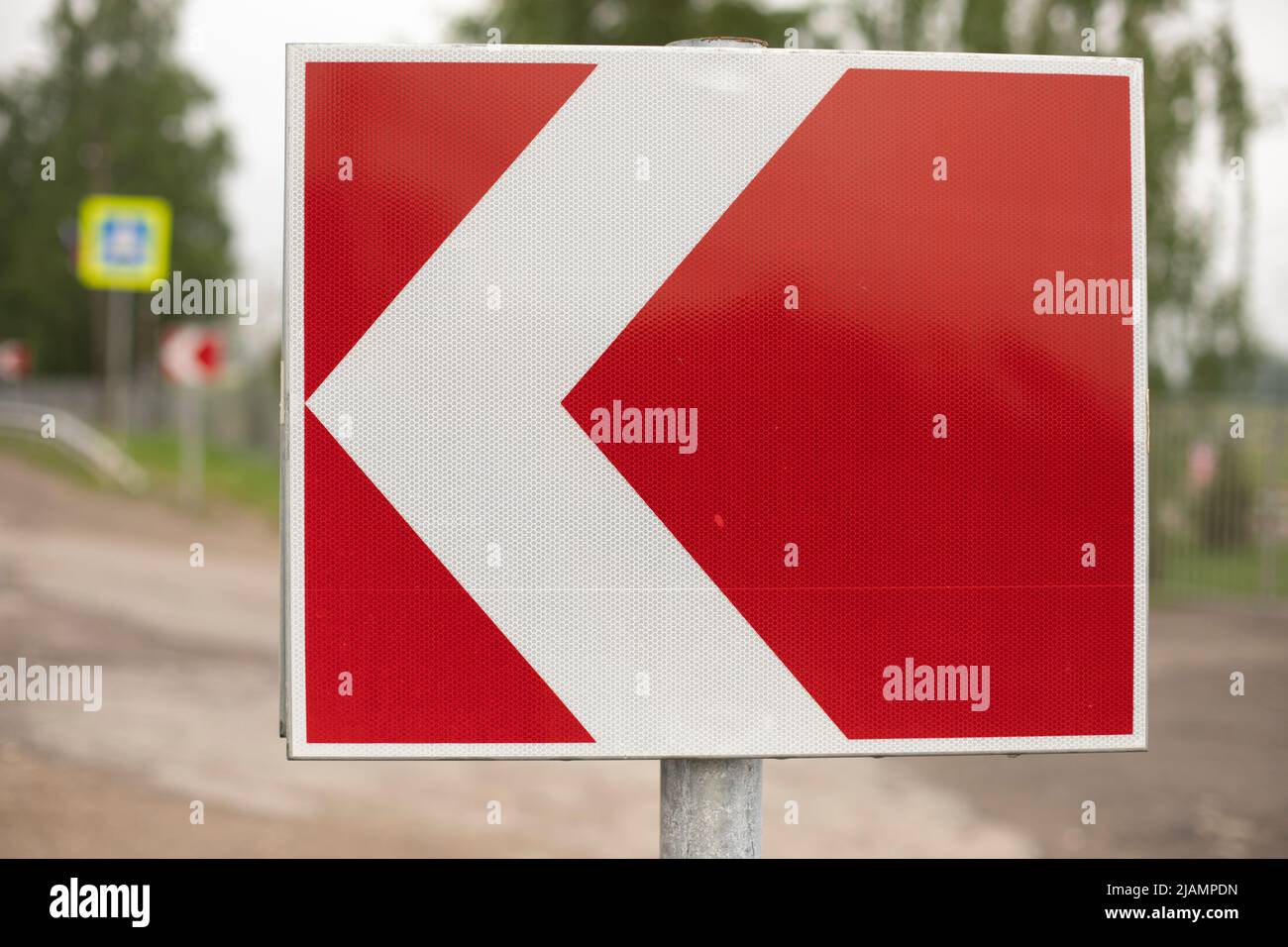 Sign sharp turn. Red road sign. Arrow pointer on road. Infrastructure for transport. Stock Photo