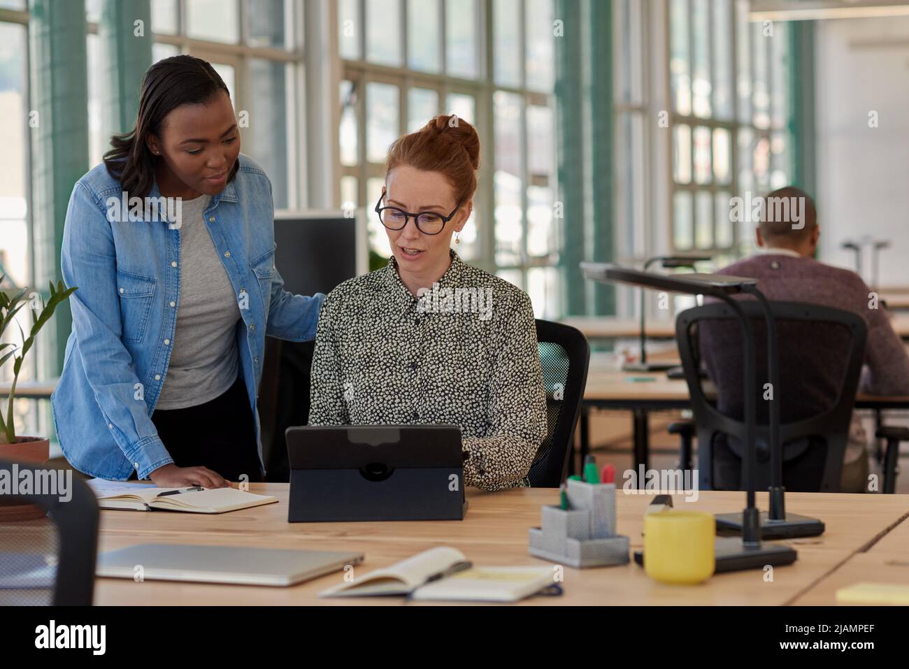 Two diverse businesswomen working on a tablet together in an office Stock Photo