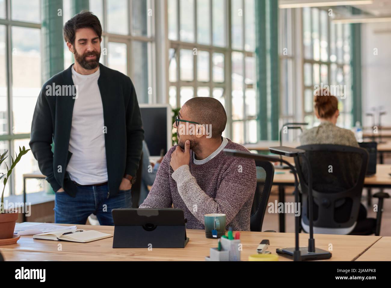 Two diverse businessmen talking while working on a digital tablet Stock Photo