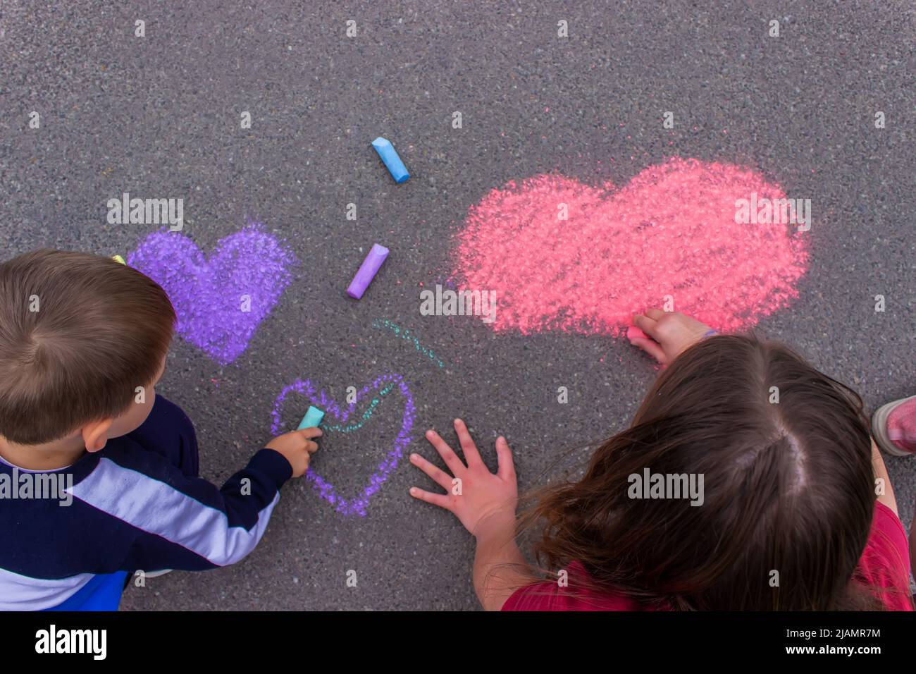 child's hand draws hearts, draws with chalk on the pavement. selective