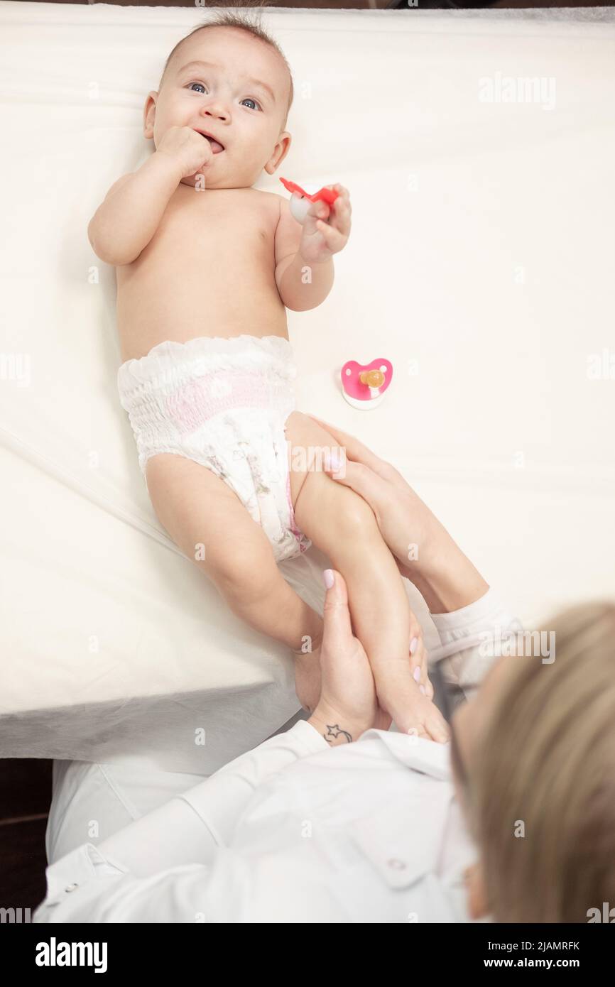 Female masseur doing baby massage for foot little infant baby child play toy Stock Photo