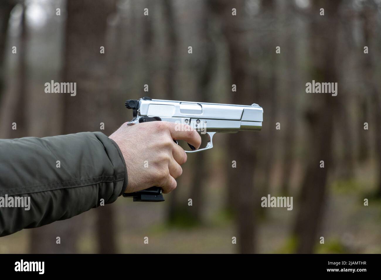 A man is holding a gun and aiming. A hand holding a gun about to shoot with a pistol Stock Photo