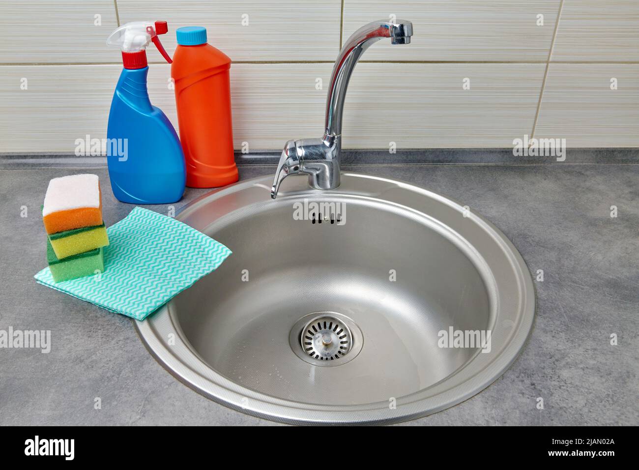 Round metal sink, cleaning agent, wipes and foam sponges Stock Photo
