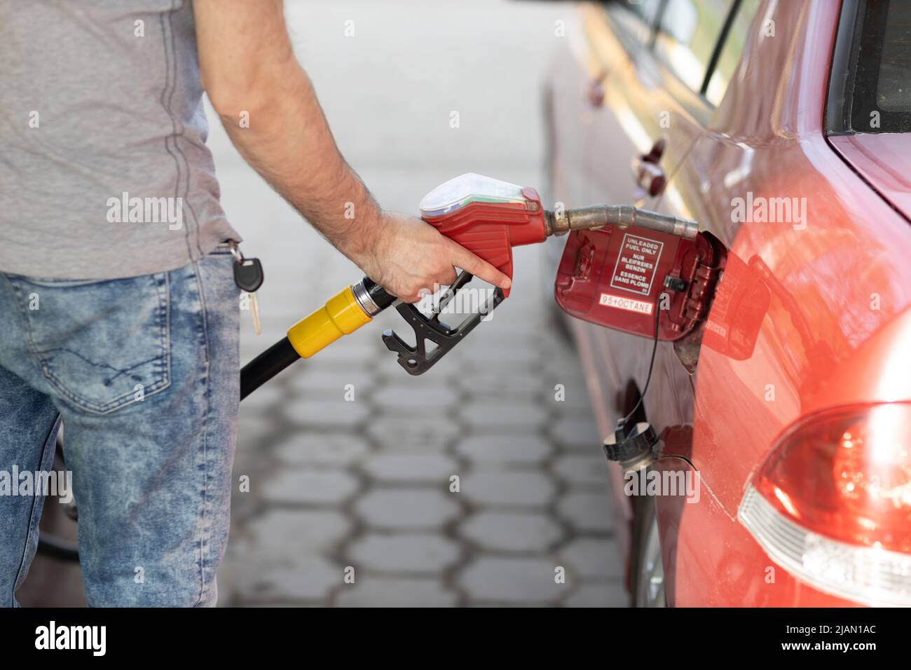 Man filling fuel tank in his hand at gas station. Sanctions economy crisis Stock Photo